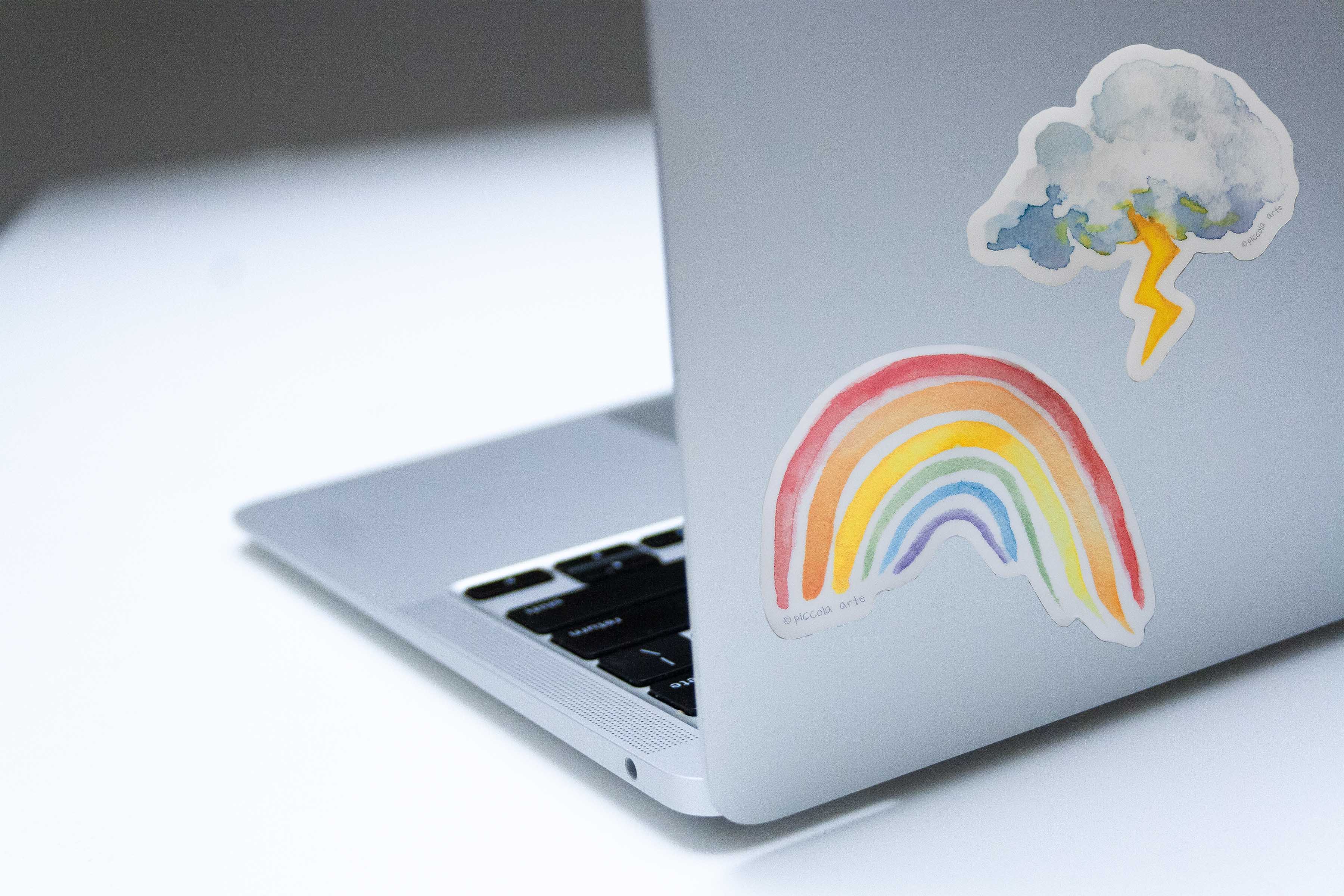 Laptop with rainbow and cloud sticker on a light background