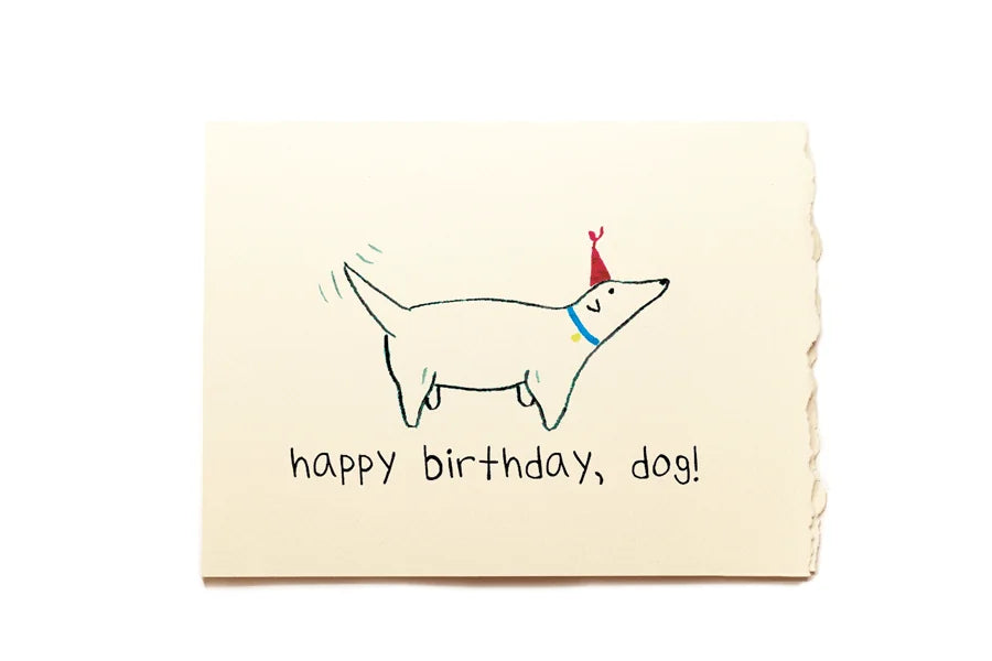 Birthday card with a drawing of a dog wearing a party hat and text 'happy birthday, dog!' on a beige background.