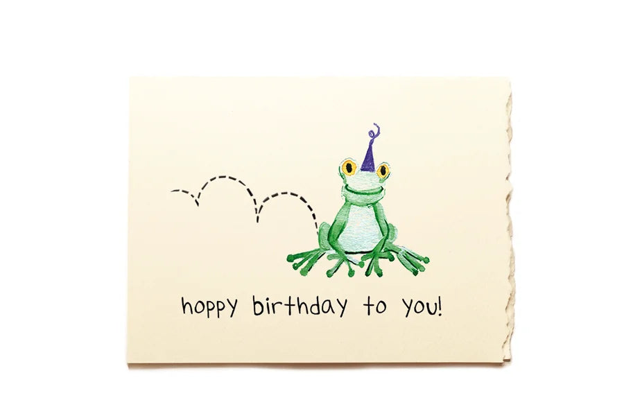 Birthday card with a green frog wearing a purple hat and 'hoppy birthday to you!' text on a beige background.