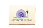 Greeting card with a purple snail and red hat on a beige background, featuring the text 'Happy Belated Birthday!'.
