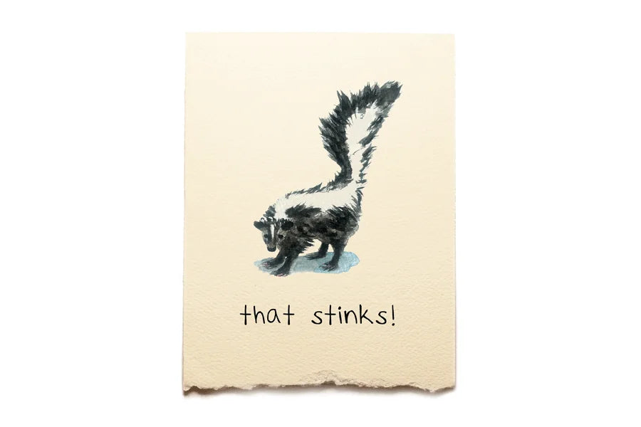 Notebook with a skunk illustration and 'that stinks!' text on a beige background