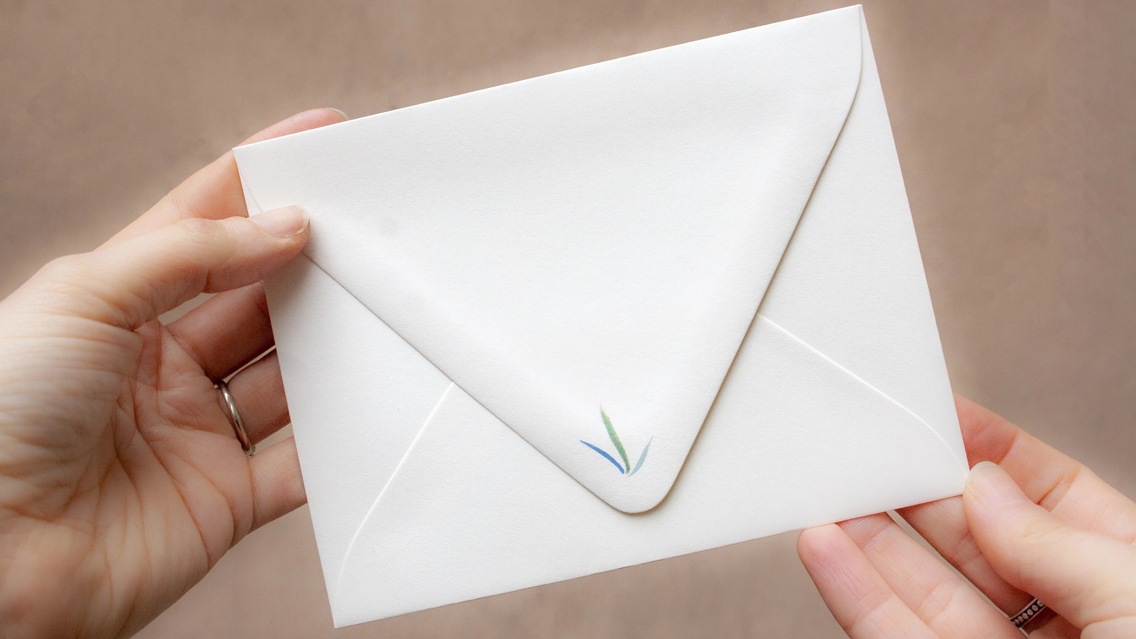 White envelope held by hands against a neutral background