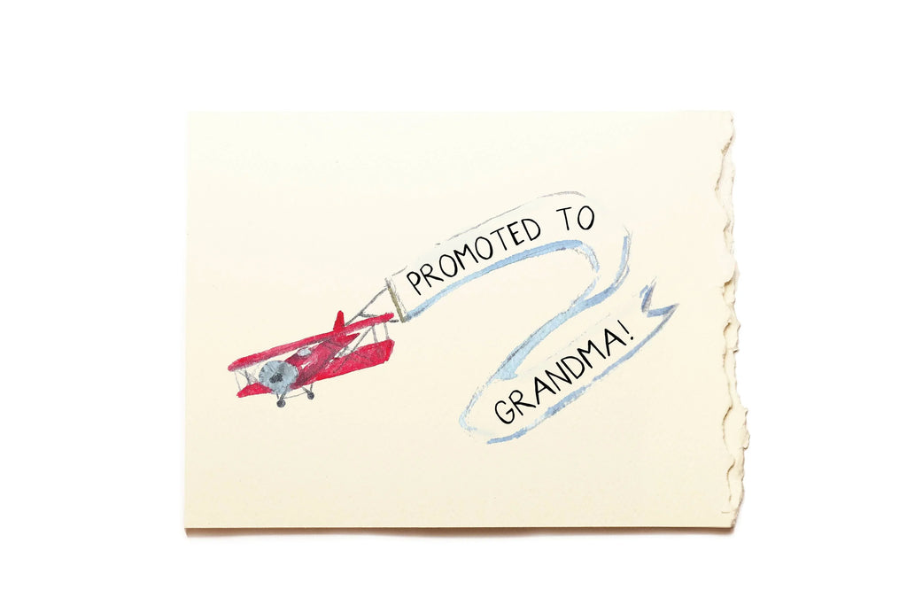 Note with a red airplane illustration and text 'Promoted to Grandma!' on a white background