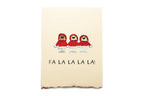 Notebook with three red-suited figures and 'FA LA LA LA LA!' text on a beige background