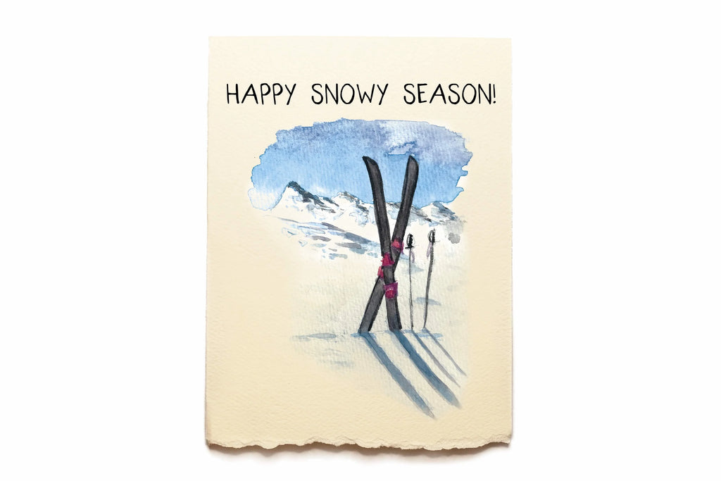 Card with skis and snow, and 'Happy Snowy Season!' text on a beige background