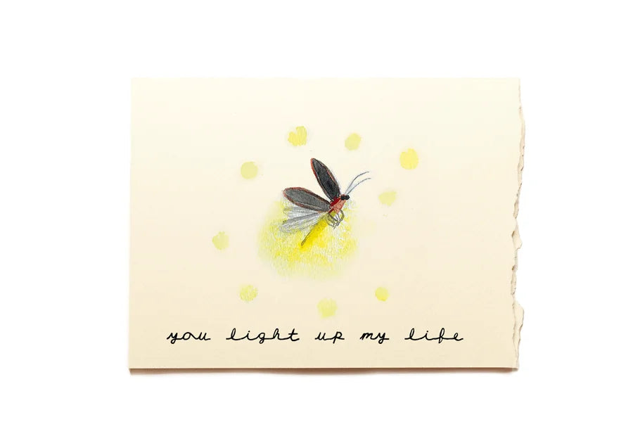 Greeting card with a firefly illustration and text 'you light up my life' on a white background