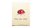 Note card with a ladybug illustration and 'miss you, lady!' text on a beige background