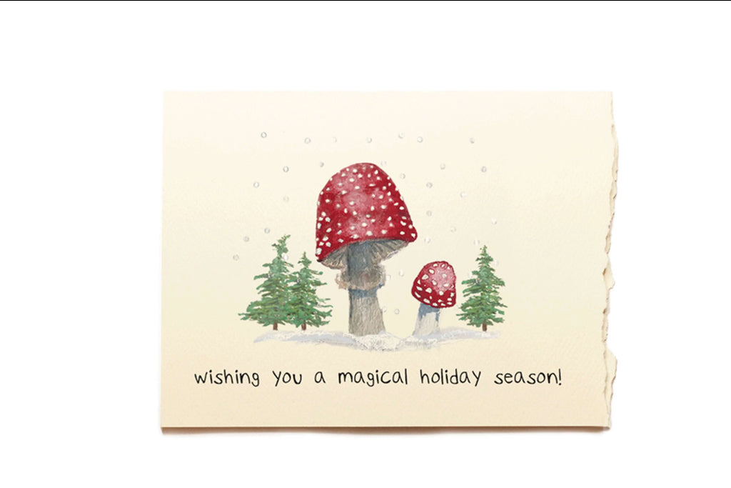 Greeting card with mushrooms and trees, text 'wishing you a magical holiday season!' on a white background