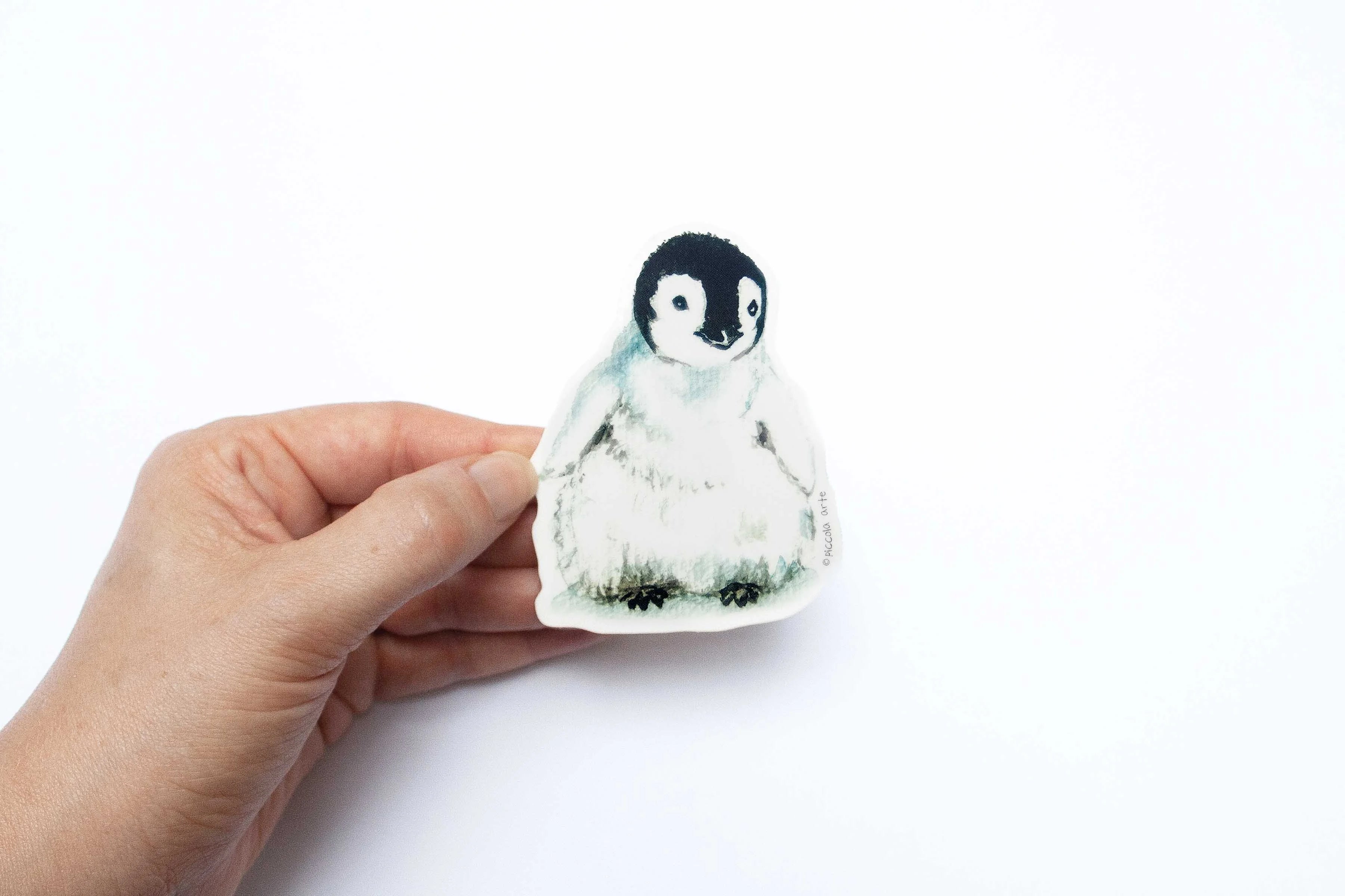 Hand holding a penguin-shaped object against a white background