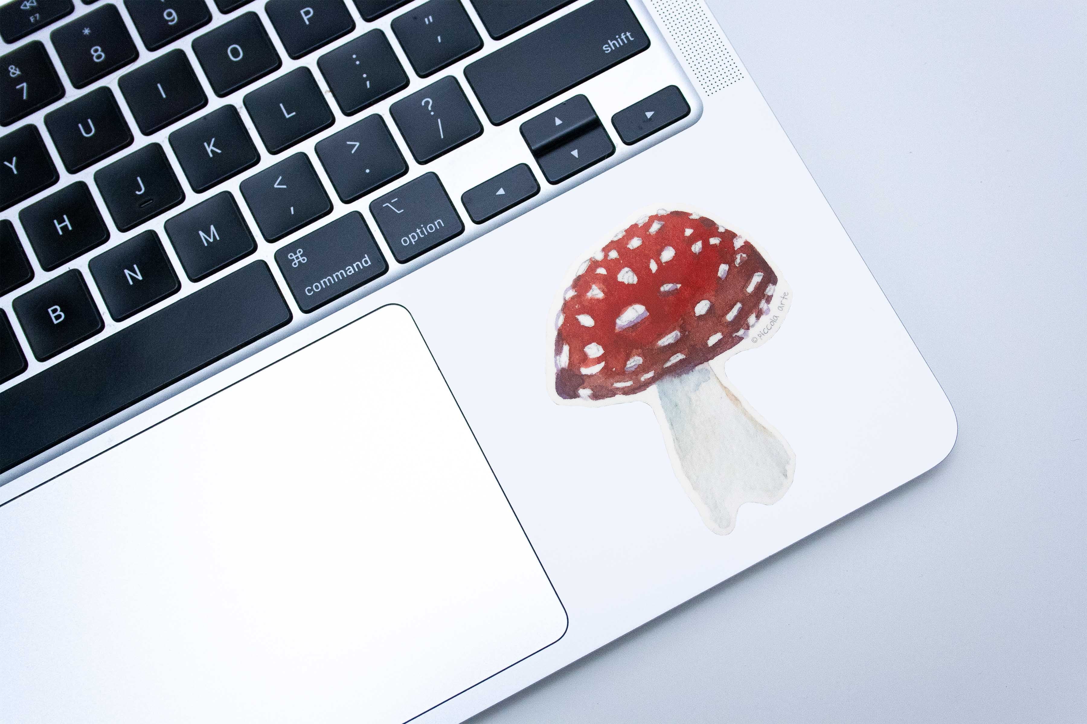 Laptop with a red and white mushroom sticker on the trackpad