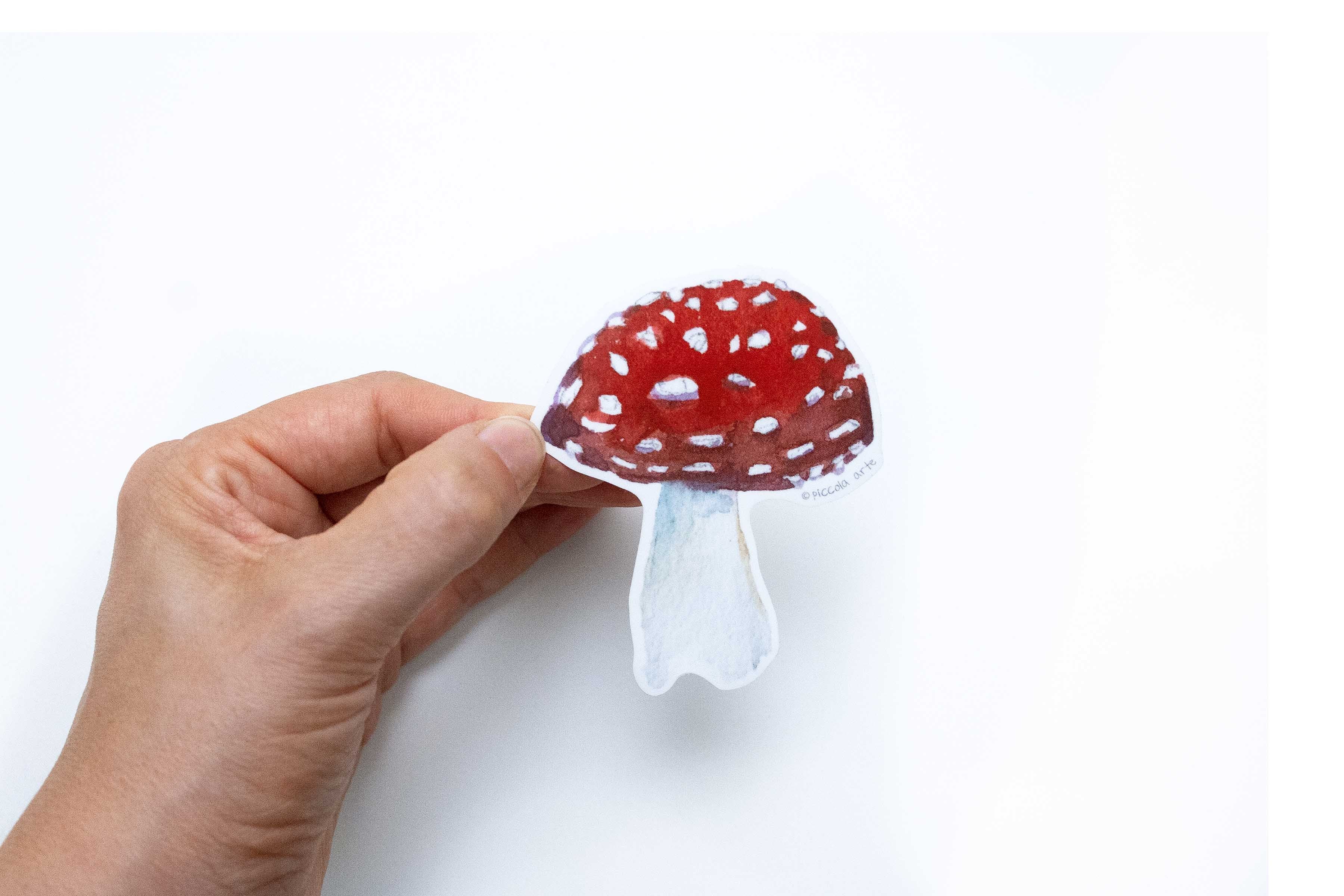 Hand holding a red and white mushroom-shaped object on a white background