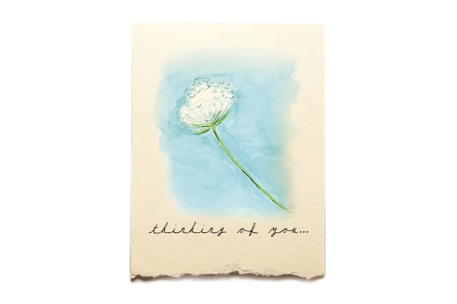 Card with a white flower illustration and 'thinking of you' text on a blue watercolor background.