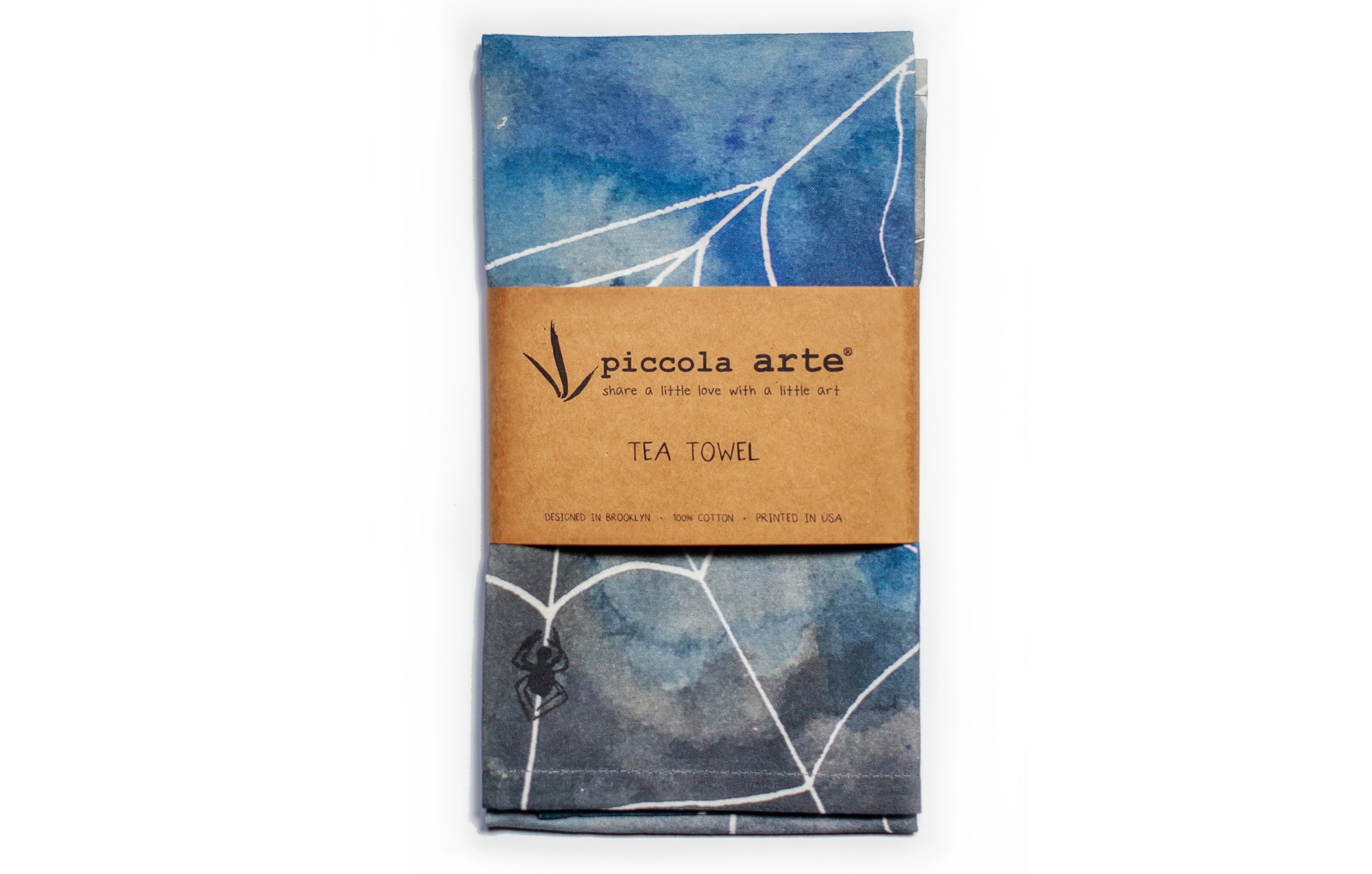 Tea towel with blue leaf pattern and Piccola Arte branding on a white background