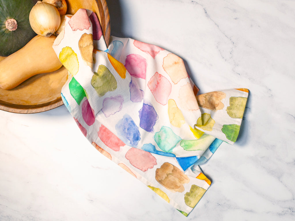 Colorful abstract patterned towel on a marble surface with a pumpkin and onion.