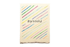 Notebook with colorful diagonal lines and '#grateful' text on a white background