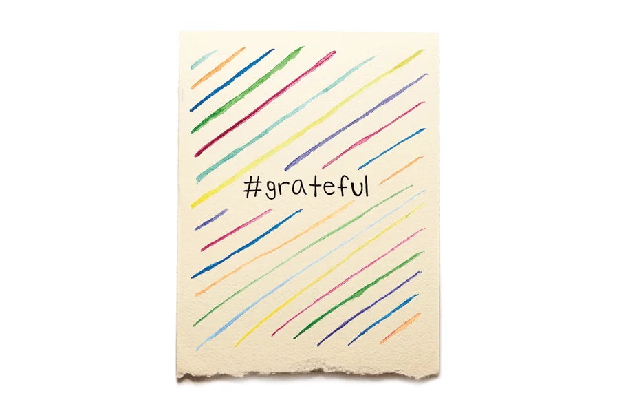 Notebook with colorful diagonal lines and '#grateful' text on a white background
